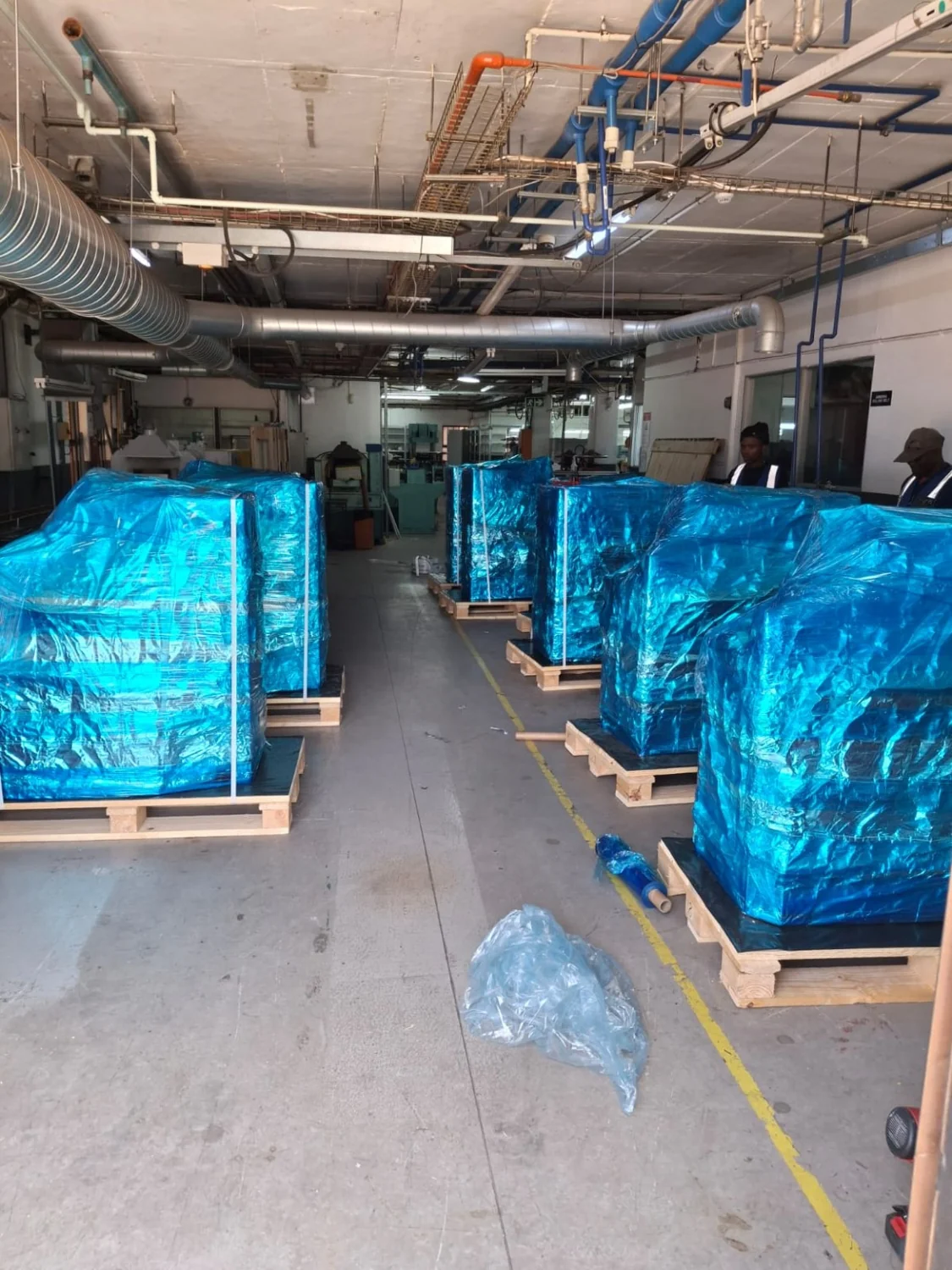 Actual project showing rows of packaged equipment on timber bases inside a factory